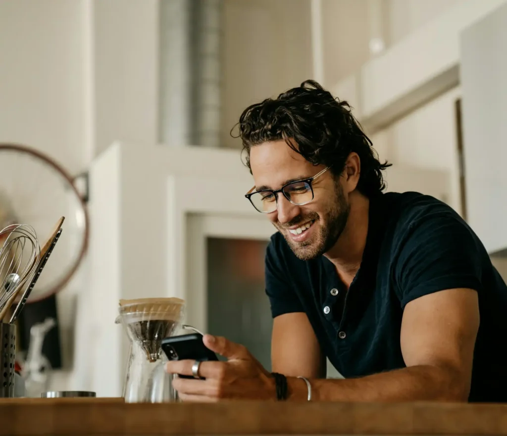 Man som är glad och läser något på sin telefon