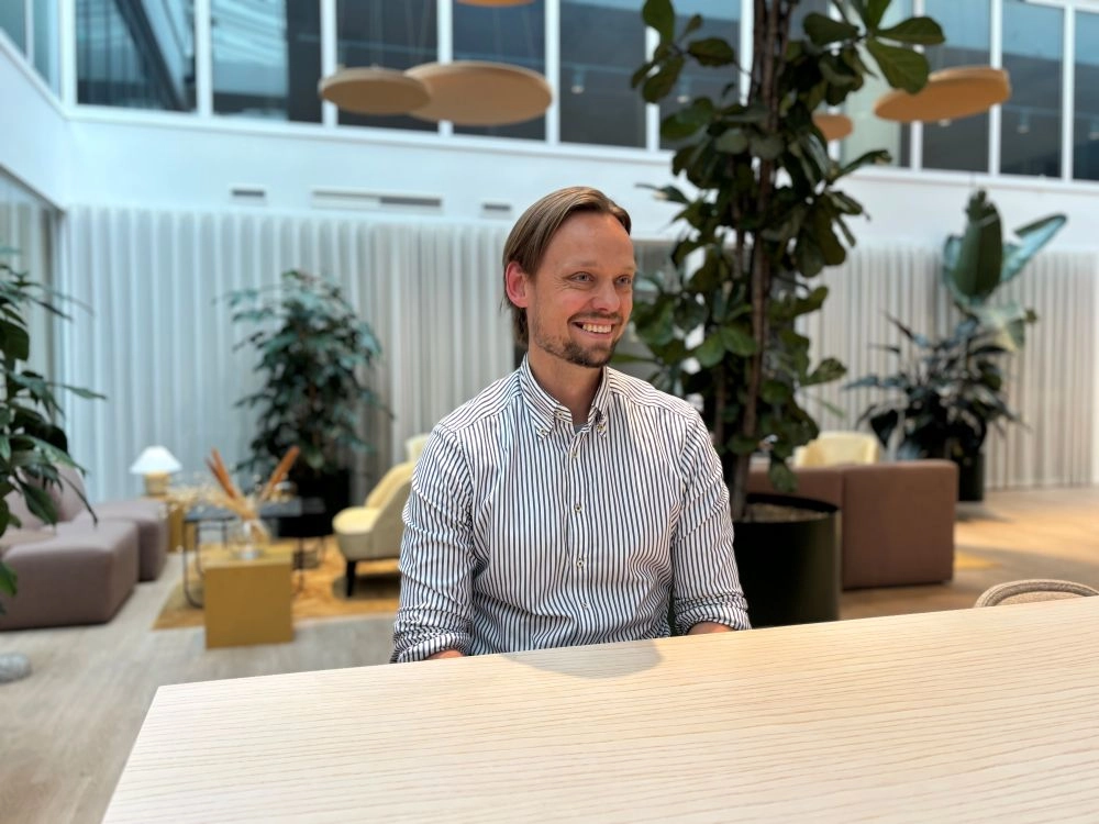 Erik Oresten från Onify sitter vid ett ljust träbord i ett öppet kontorslandskap