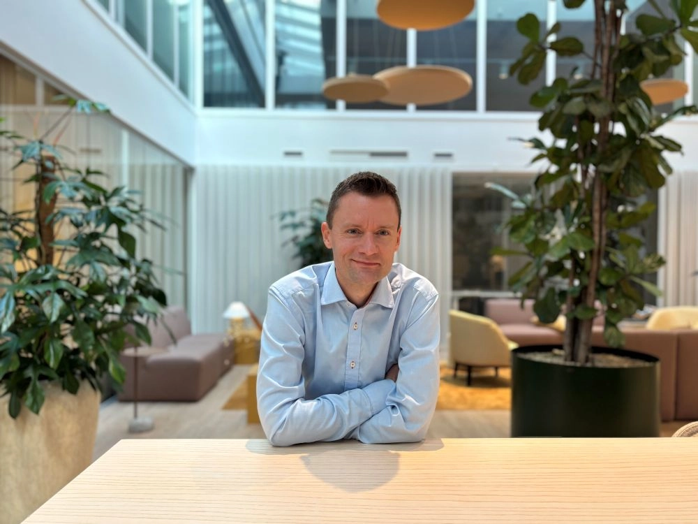 Tony Aronsson från Onify sitter vid ett ljust träbord i ett öppet kontorslandskap