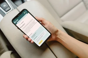 Bild visar en hand som håller i en mobil i en bil. Skärmen visar Onify Mina Barn.