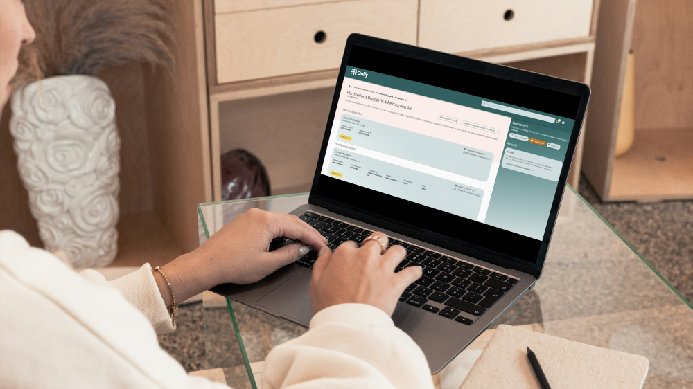 En tjej sitter och jobbar på sin laptop som står på ett skrivbord.